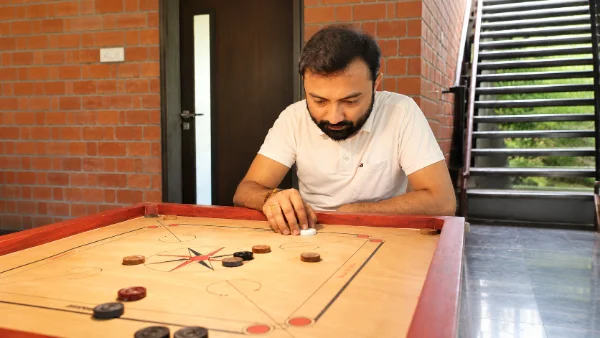 Focused Carrom Match in a Brick-Walled Room-600x338